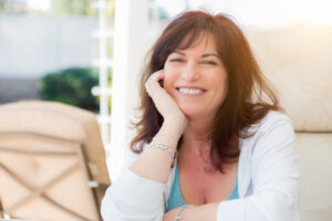 Middle-aged woman smiling on a brightly lit patio