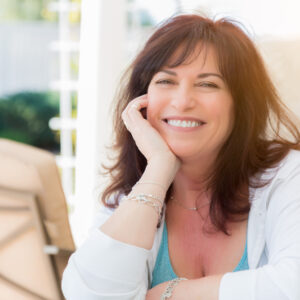 Middle-aged woman smiling on a brightly lit patio